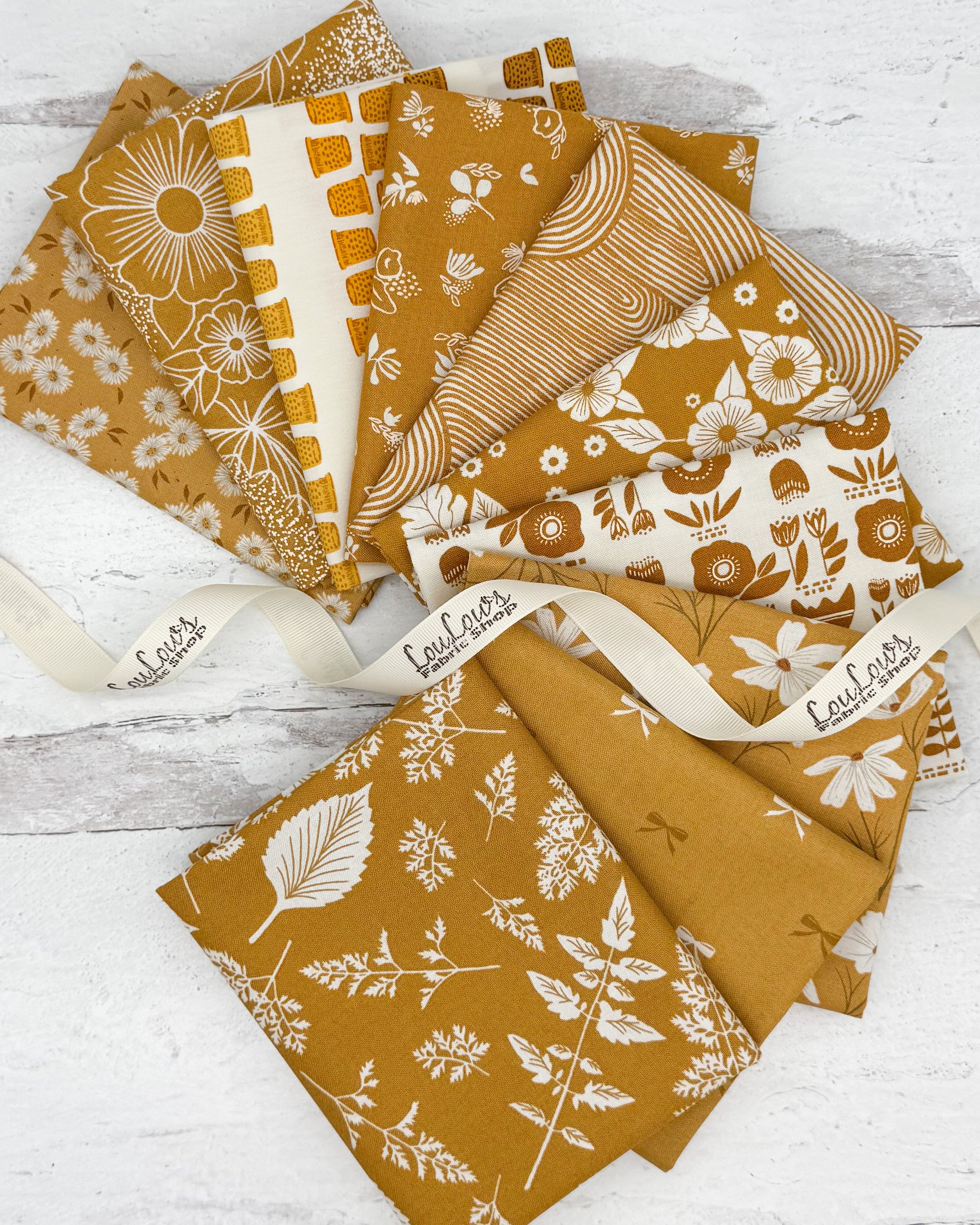 10 mustard/honey colored fat quarters with mostly with a floral or botanical print. 