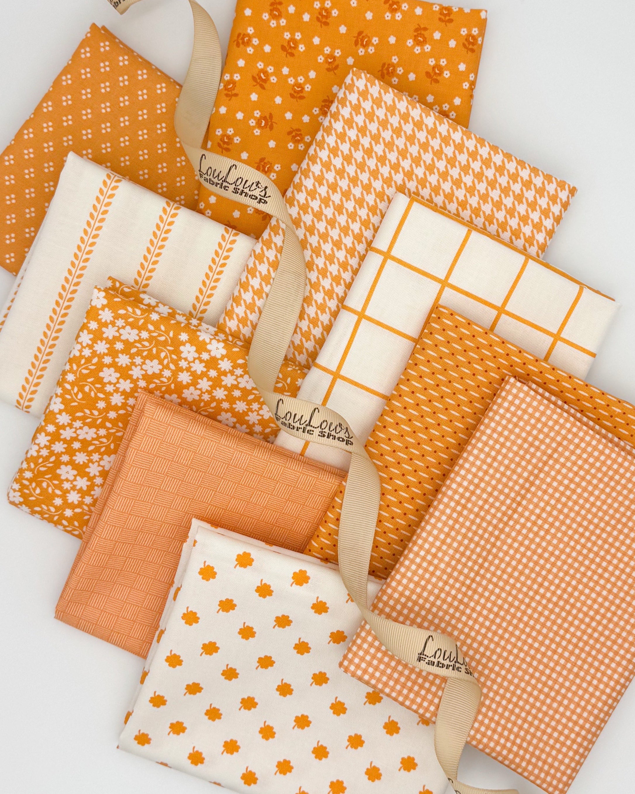 Collection of 10 fat quarters with a bright orange background or ivory background with orange accents. 