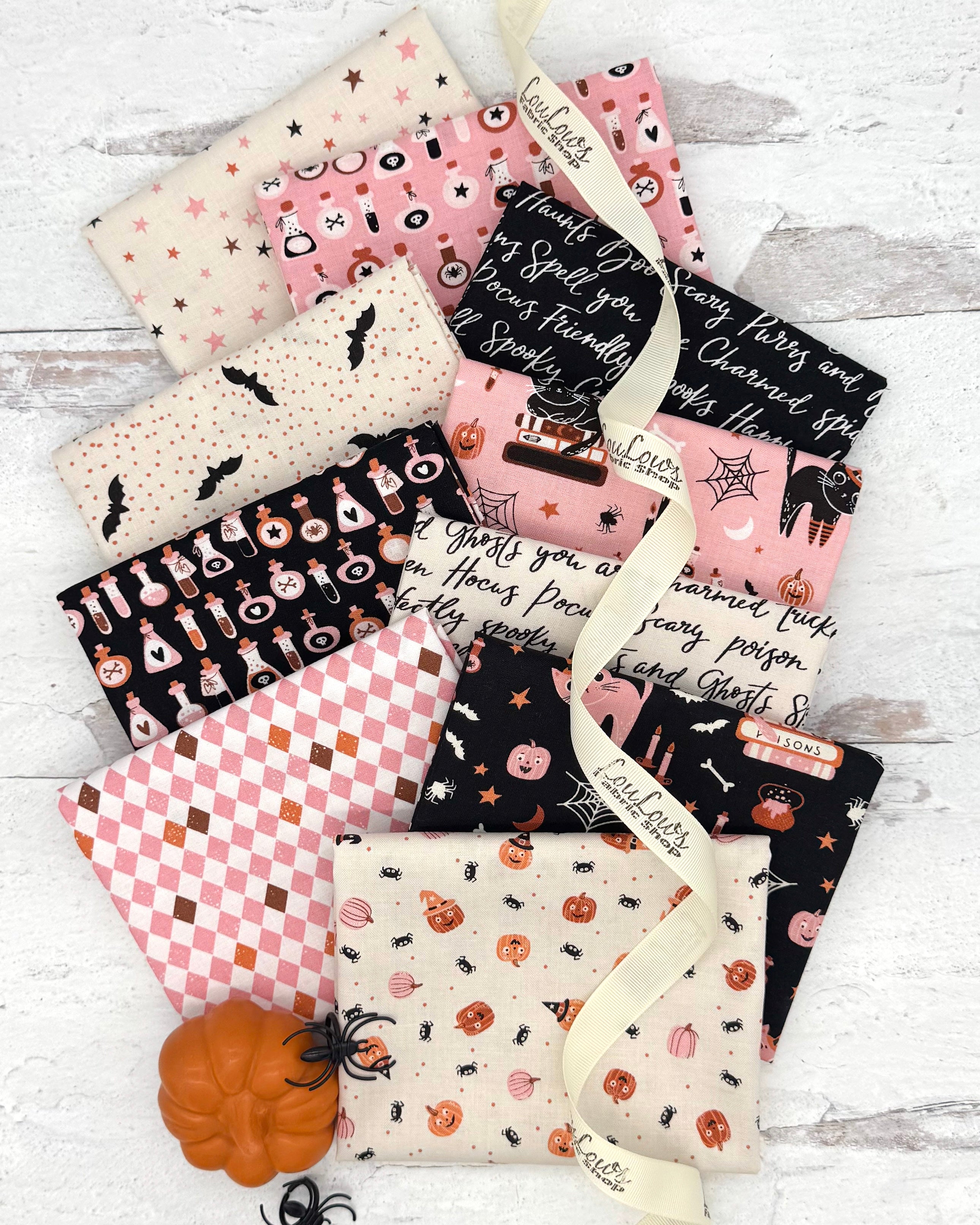 10 Halloween themed fat quarters in light pinks, creams and blacks. Prints include pumpkins, stars, potions, cats and bats. 