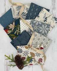 Collection of 10 fat quarters with holiday prints on blue and cream background fabrics 