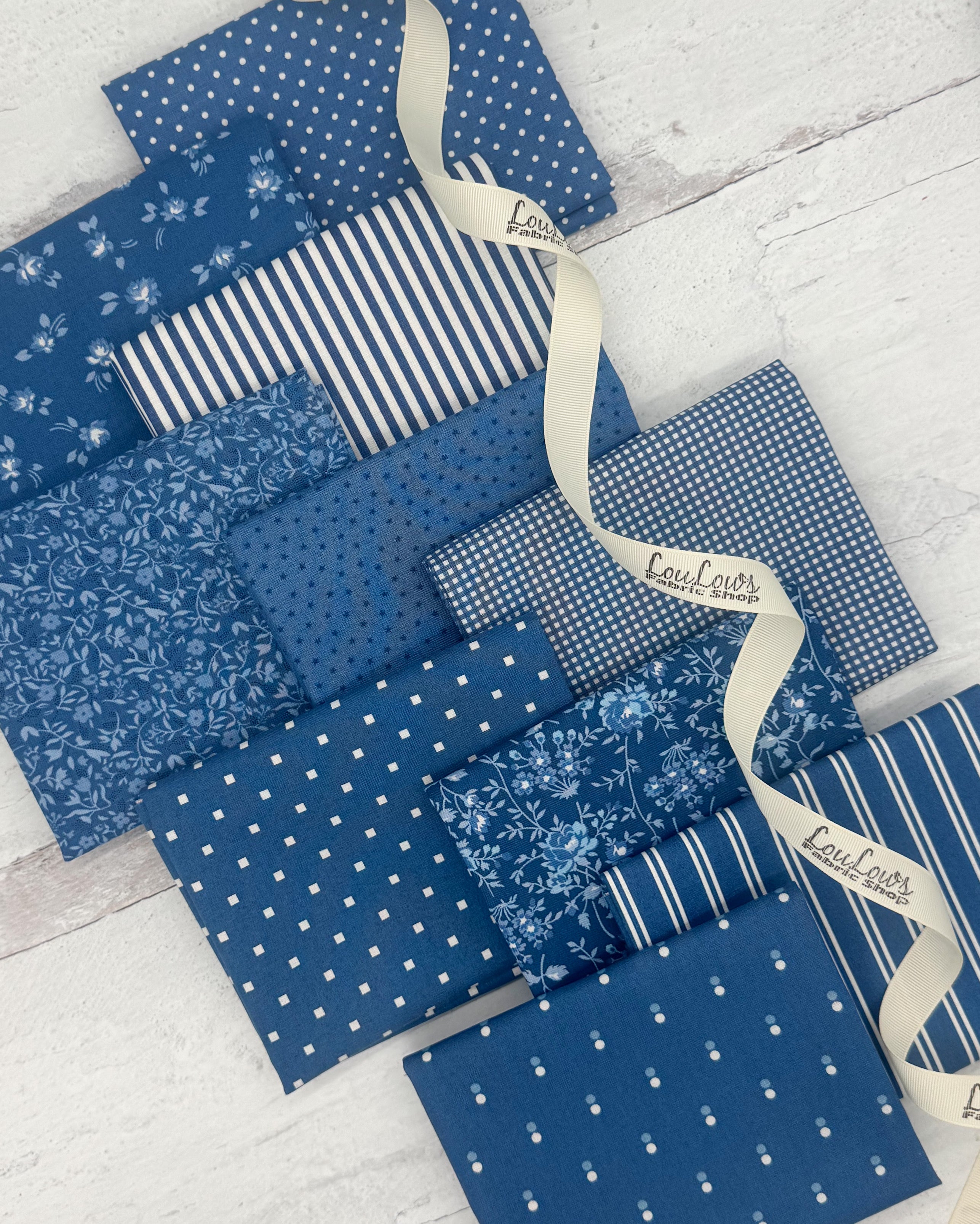 Collection of 10 fat quarters in a denim blue color. Prints include dots, florals, stripes and geometrics. 