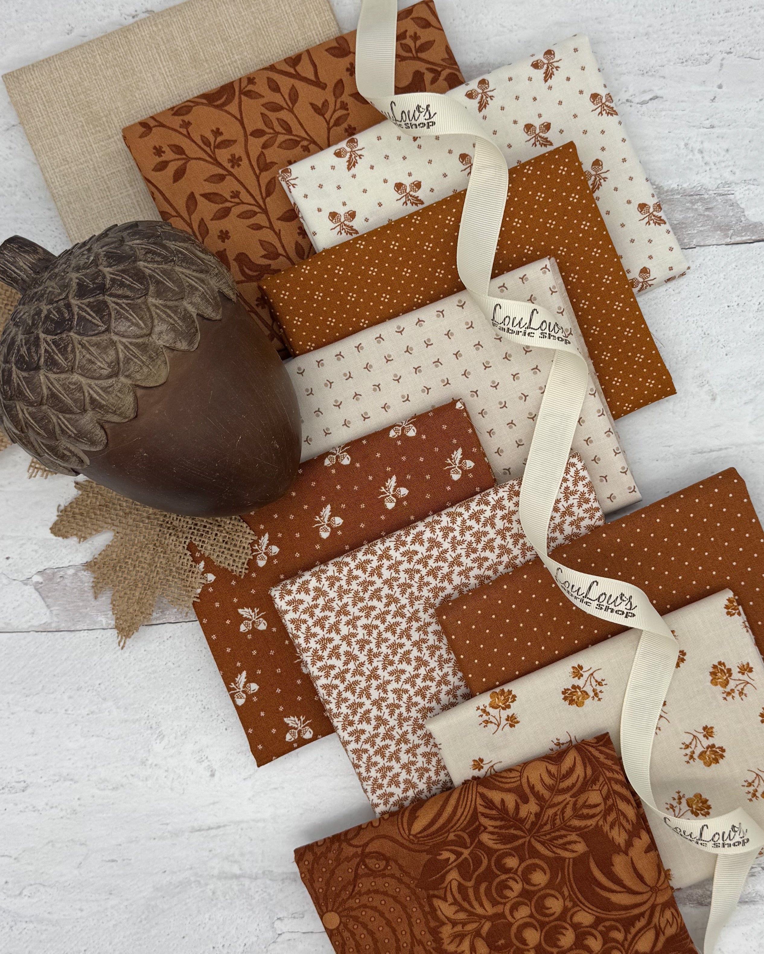 10 fat quarters, 5 with a cinnamon colored background, 5 with off white background. Prints include acorns, dots and florals. 